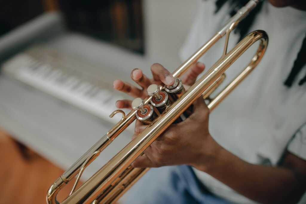 Close-up of a child playing the trumpet indoors with blurred keyboard background.